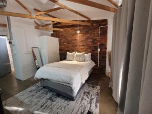 a bedroom with a bed and a brick wall at Trendy apartments _ @ Craftsmanship on main in Johannesburg