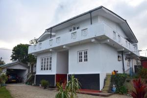a white house with a balcony at Carmalin Holiday Bungalow in Nuwara Eliya