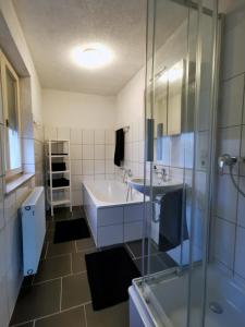 een badkamer met een bad, een wastafel en een douche bij 3 Zimmer Ferienwohnung mit eigenem Garten Trossingen in Trossingen