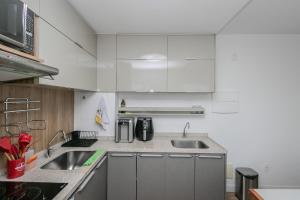 a kitchen with white cabinets and a sink at 2 quartos c/ AC na Savassi in Belo Horizonte