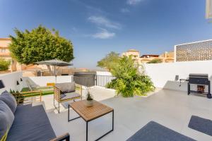 an outdoor patio with furniture and a grill at Designer loft with pool, with gigantic terrace and private parking & in the city centre in Adeje