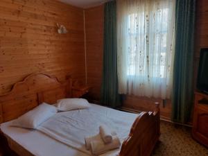 1 dormitorio con 1 cama con sábanas blancas y ventana en Complex Țurcana Transalpina, en Şugag