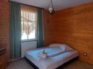 1 dormitorio con 1 cama en una pared de madera en Complex Țurcana Transalpina, en Şugag