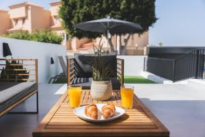 uma mesa com um prato de croissants e dois copos de sumo de laranja em Designer loft with pool, with gigantic terrace and private parking & in the city centre em Adeje