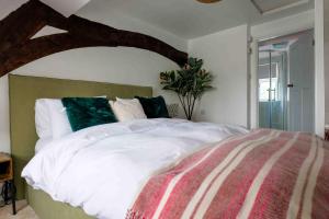 1 dormitorio con 1 cama grande con sábanas blancas y almohadas verdes en Remarkable 1-Bed Cotswolds Cottage in Finstock, en Chipping Norton