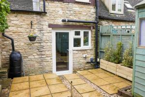 a stone house with a white door and a patio at Remarkable 1-Bed Cotswolds Cottage in Finstock in Chipping Norton