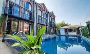 a house with a swimming pool in front of a building at Kave Hotels - Pondicherry in Pondicherry