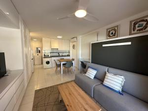 a living room with a blue couch and a kitchen at PLAYA Denia BEACH ESTUDIO in Denia