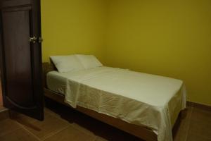 Cama pequeña en habitación con paredes verdes en Casa habitacion, 4 dormitorios, en Tarapoto