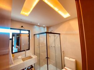 une salle de bain avec douche, toilettes et miroir dans l'établissement Villas Manatee - Patacho - AL, à Porto de Pedras