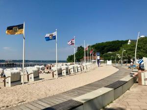 einen Strand mit Flaggen und Stühlen und einen Pier in der Unterkunft Ostseewohnung Nr. 14 - Villa Mare - in Glücksburg