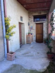 une terrasse couverte d'un bâtiment avec une porte et des plantes dans l'établissement Cantina nel Castello, à Montegiovi