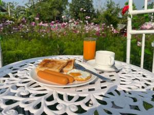 a table with a plate of food and toast and orange juice at The P2 Hotel in Mae Sot