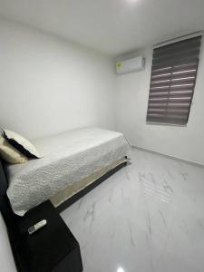 uma cama num quarto branco com uma janela em Apartamento excelente ubicación em Barranquilla