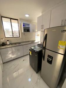 uma cozinha com um frigorífico de aço inoxidável e armários brancos em Apartamento excelente ubicación em Barranquilla