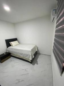 um quarto com uma cama num quarto branco em Apartamento excelente ubicación em Barranquilla