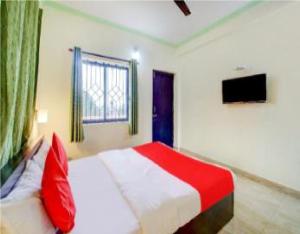 Hotel Adam's Baga Beach Resort Goa - 2 minutes walk from Baga Beach في باغا: غرفة نوم بسرير احمر وبيض وتلفزيون