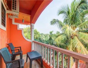 a balcony with two chairs and a palm tree at Hotel Adam's Baga Beach Resort Goa - 2 minutes walk from Baga Beach in Baga