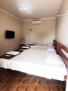 a large white bed in a room with a tv at Hotel Los Angeles Aeroporto in Várzea Grande