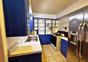 uma cozinha com armários azuis e um frigorífico de aço inoxidável em Cozy 3br By Houston Ship Channel em Houston