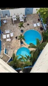 uma vista superior de duas piscinas com cadeiras e palmeiras em Villa Del Sol Hotel Fortaleza em Fortaleza