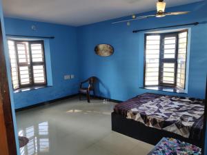 a blue bedroom with a bed and two windows at Sea Shade in Udupi