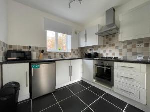 uma cozinha com armários brancos e electrodomésticos de prata em Spacious 2BR Apartment w/Parking Near City Centre em Sheffield