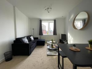sala de estar con sofá negro y mesa en Spacious 2BR Apartment w/Parking Near City Centre, en Sheffield