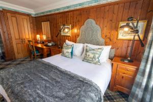 a bedroom with a bed and a desk and a table at Dunkeld House Hotel in Dunkeld