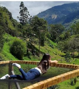 a woman laying on a bench looking at a mountain at Cabaña Canto de las Aguas Cañón del Combeima in Ibagué
