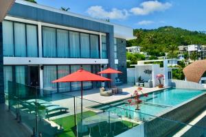 una piscina con ombrellone rosso e un edificio di Villa Savoy Sharm Samui a Chaweng Noi Beach