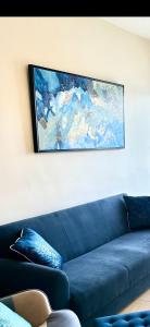 eine blaue Couch in einem Zimmer mit einem Gemälde an der Wand in der Unterkunft PALLINIO COURT 402 Fig Tree Bay- Protaras Beach, IASONOS STR 7A in Protaras