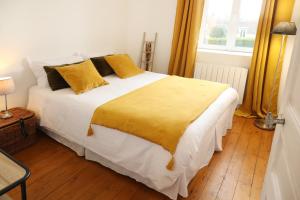 ein Schlafzimmer mit einem großen weißen Bett mit gelben Kissen in der Unterkunft Maison Le Charmant La Boîte En Plus in Chamant