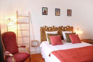 ein Schlafzimmer mit einem Bett mit einem roten Stuhl und einer Leiter in der Unterkunft Maison Le Charmant La Boîte En Plus in Chamant