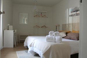 a white bedroom with two towels on a bed at Serendipia in Ávila