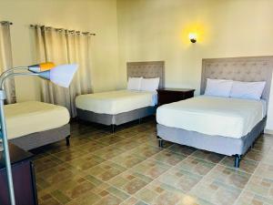 a hotel room with two beds and a lamp at Casa Primavera SPS in San Pedro Sula