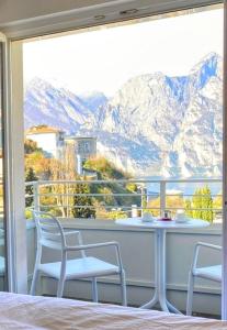 een balkon met een tafel en stoelen en uitzicht op de bergen bij Albergo Garni Francesco in Nago-Torbole