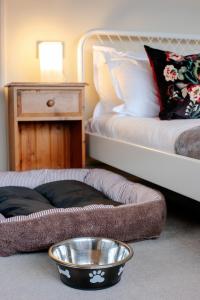 a dog bed with a bowl on the floor next to a bed at Bendene Townhouse - Exeter in Exeter