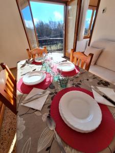 una mesa de comedor con platos rojos y blancos. en apartament Eliette 3 en Bagá