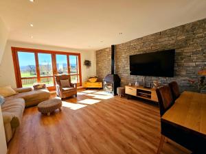 sala de estar con pared de piedra y TV de pantalla plana en El Rincón del Pirineo, en Senegüé