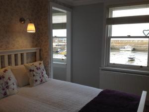 a bedroom with a bed and a window with a boat in the water at Harbour View 23 Shorehead in Stonehaven