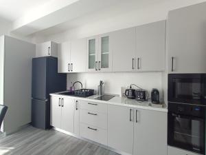 a kitchen with white cabinets and a black refrigerator at Apartament Maia Baile Felix in Baile Felix