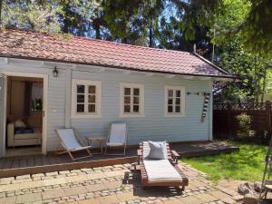 ein kleines weißes Haus mit zwei Stühlen und einem Tisch in der Unterkunft Tulipanek - domek letniskowy z ogródkiem in Stegna