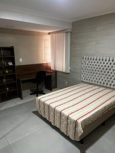 a bedroom with a bed and a desk and a desk at Linda Casa com Estacionamento in Juiz de Fora