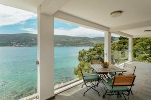 a table and chairs on a porch with a view of the water at Apartments Joy in Herceg-Novi