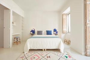 a white bedroom with a bed and a rug at Casa Pavão in Lisbon