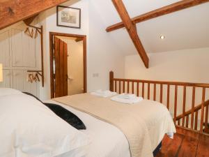 two beds in a room with wooden beams at The Coach House in Pwllheli