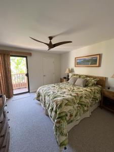 Tropical Maui Kamaole B-Bldg في ويليا: غرفة نوم بسرير ومروحة سقف