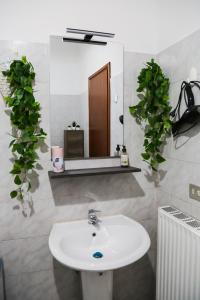 baño con lavabo, espejo y plantas en Guest House Fontanesi, en Reggio Emilia