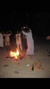 un gruppo di persone che ballano intorno al fuoco sulla spiaggia di Felucca Sailing Boat Overnight Experience a Aswan